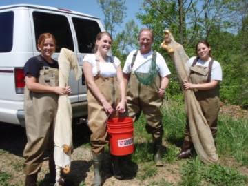 Four student in chest waders following an ifish field  ID test